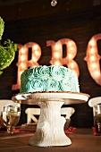 Chocolate Cake with Green Icing on a Faux Wood Cake Stand; On a Table in a Barbecue Restaurant