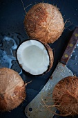 Fresh Coconuts with a Large Knife; One Cracked Open with Spilled Coconut Milk