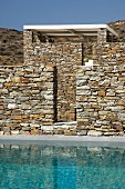 Stone wall and bright turquoise pool in Greek hilly landscape