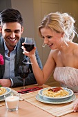 Junges Paar trinkt Rotwein zu Spaghetti mit Tomatensauce im Restaurant