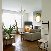 Mix of furniture styles in a living room with delicate wrought iron chair and rococo style side tables next a modern upholstered sofa