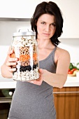 A woman holding a storage jar full of pulses