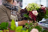 Florist holding summer bouquet of hydrangeas, amaranthus and roses