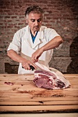 A butcher cutting a layer of fat off a ham