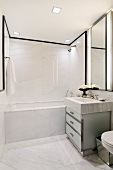 Designer marble bathroom - washstand with marble surround and glass base unit next to bathtub