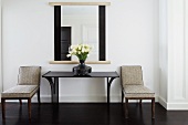 Upholstered chairs next to console table and mirror in classic setting