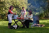 Women cooking tomato sauce in a barrel outdoors