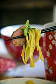 Chinese noodle salad with duck breast on chopsticks