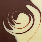 The surface of white and dark chocolate sauces, partly spiralled together