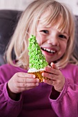 Kleines Mädchen hält Tannenbaum-Cupcake in den Händen