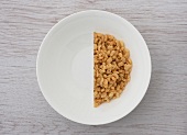Halbierte Portion Cerealien in weißer Schale (Aufsicht)