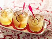 An apple drink (cider and whiskey) with sliced apples and ice cubes