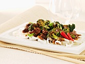 Beef and broccoli stir-fry with chillies on a bed of rice noodles