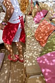 Mann mit roter Schürze vor Sitzbank mit bunten Kissen auf Terrasse