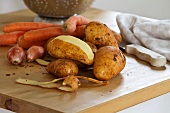 Carrots, shallots and potatoes; one potato partly peeled