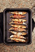 Barbecued fish wrapped in bacon