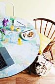 Im jugendlichen Stil aufgepeppter Frühstückstisch mit selbst aufgeklebter Weltkarte und Vintage Stühlen