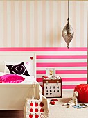 Pinkfarbene Quer- und pastellige Längsstreifen hinter Landhausbett und Nachttischkiste im Kinderzimmer