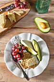 Glutenfreie Cracker mit Cheddar, Trauben & Avocado auf Teller