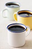 Black coffee in three enamel mugs