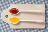 Two spoons with oil and vinegar on a chopping board