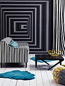 Black and white upholstered armchair and black coffee table on a white wood flooring in front of a wall with optical illusion wallpaper