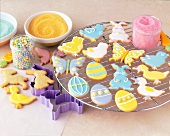 Assorted Decorated Easter Cookies on a Cooling Rack with Sprinkles and Cookie Cutters