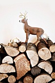Small plastic stag figurine and silver Christmas tree baubles on stacked firewood