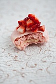 A rose macaroon topped with diced strawberries