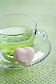 A heart-shaped vanilla macaroon with a cup of green tea