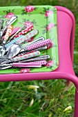 Colourful cutlery on a floral tray in the garden