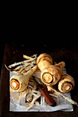 Several parsnips, partly peeled, on newspaper