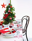 A table laid for Christmas dinner decorated with a mini Christmas tree