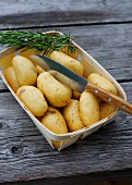 Potatoes and rosemary with a knife in a woodchip basket