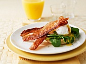 An English muffin with bacon, rocket and a poached egg