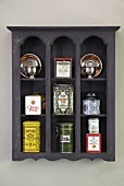 Various tea caddies in wall-mounted shelving unit of grey-stained wood