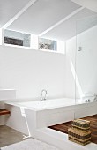 Designer bathroom with bathtub on platform opposite shower area with glass partition