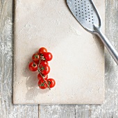 A floured stone slab with cherry tomatoes and a fish slice