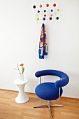 Bauhaus swivel chair with blue cover and side table in front of classic, wall-mounted coat rack