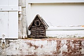 Wicker bird box on weathered stone step outside house