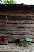 Schrift love aus Lichtschlauch an der Aussenwand einer rustikalen Holzhütte