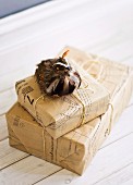 Presents wrapped in pale brown paper cutting patterns and bird ornament with real feathers