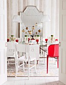 Christmas tree baubles hanging over festively set table in front of full-length mirror