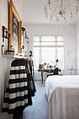 Bedroom with double bed, skirts hanging up and antique escritoire below window