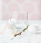 Empty glass with Easter decorations (egg shells, pussy willow, feathers)