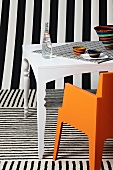 White table and orange chair surrounded by various patterns of black and white stripes