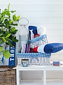 Nautical-style lantern and cushions in basket on bench against white house facade