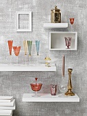 Glasses on white shelving units mounted on grey wall