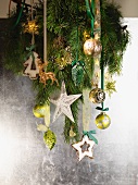 Fir branch with Christmas decorations hanging on silver wall