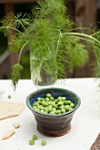 Peas in a small dish and dill in a glass